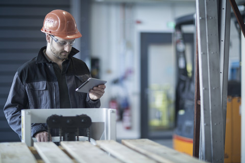 Junger Techniker arbeitet mit Tablet-PC, Paletten, lizenzfreies Stockfoto