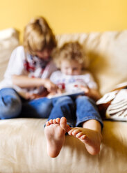 Füße eines kleinen Jungen, der mit seinem Bruder auf der Couch sitzt, Nahaufnahme - MGOF001740
