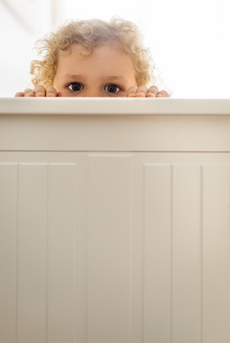 Kleiner Junge versteckt sich hinter einer Holzwand, lizenzfreies Stockfoto