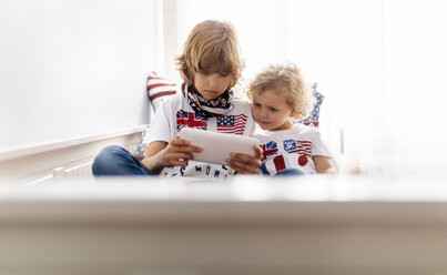 Zwei Jungen spielen mit digitalem Tablet zu Hause - MGOF001757