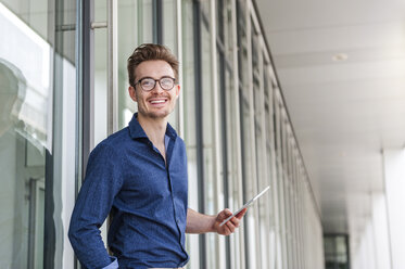 Porträt eines jungen Geschäftsmannes mit digitalem Tablet vor einem Bürogebäude - DIGF000312