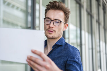 Porträt eines jungen Geschäftsmannes mit digitalem Tablet vor einem Bürogebäude - DIGF000313