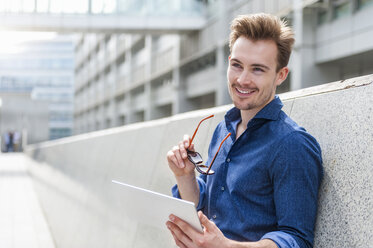 Porträt eines jungen Geschäftsmannes mit digitalem Tablet, der an der Wand lehnt - DIGF000317