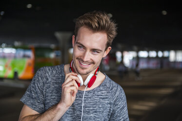 Portrait of smiling young man with headphones - DIGF000334