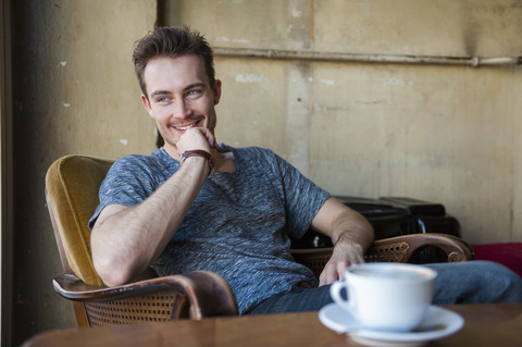 Porträt eines glücklichen jungen Mannes, der in einem Café sitzt, lizenzfreies Stockfoto