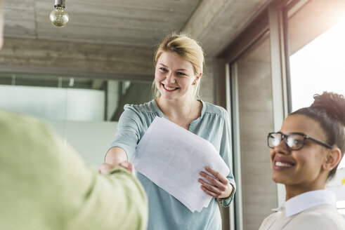 Young woman in office shaking hands with colleague - UUF007019