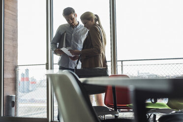 Two colleagues in office talking at the window - UUF007058