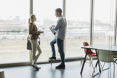 Two colleagues in office talking at the window - UUF007061