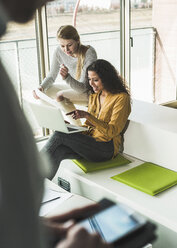 Two women in office using laptop - UUF007081