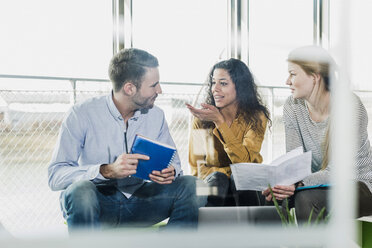 Three colleagues in office working together - UUF007087