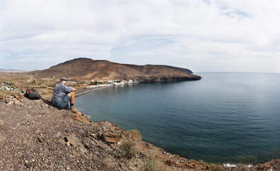 Spain, Canary Islands, Fuerteventura, southeast coast, Giniginamar, hiker looking to Lapa mountain - WWF003973