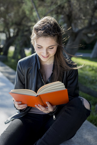 Junge Frau im Park liest ein Buch, lizenzfreies Stockfoto