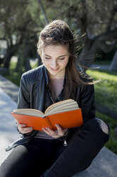 Junge Frau im Park liest ein Buch - MAUF000463