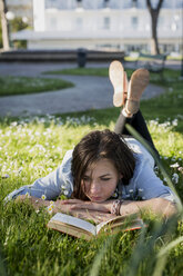 Junge Frau im Park liest ein Buch - MAUF000470