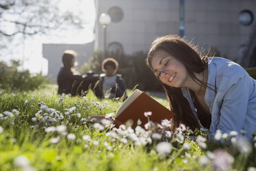 Junge Frau im Park liest ein Buch - MAUF000471