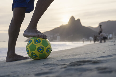 Brasilien, Rio De Janeiro, Mann steht mit Ball am Strand von Ipanema - MAUF000495