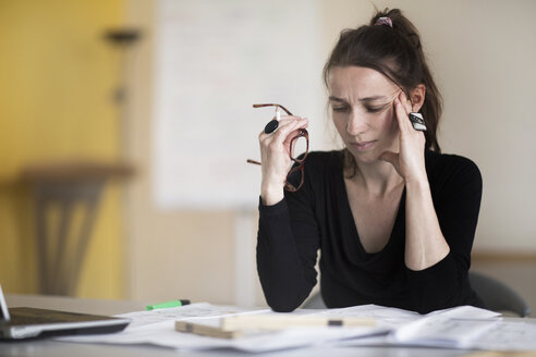 Frau im Büro betrachtet einen Plan auf dem Schreibtisch - SGF002040