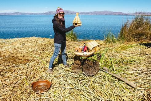 Peru, Titicacasee, Tourist auf einer schwimmenden Insel mit einer Miniaturnachbildung der Schilfhäuser der Uros - GEMF000876