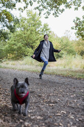 Glückliche Frau verbringt Zeit mit ihrem Hund in der Natur - MAUF000500