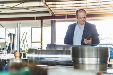 Werkstatt, älterer Mann mit digitalem Tablet vor einem Hydraulikzylinder - DIGF000350