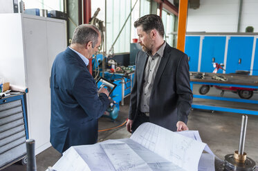 Zwei Ingenieure mit digitalem Tablet, Bauplan vor Hydraulikzylinder - DIGF000359