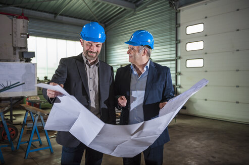 Manager mit Helm und Bauplan in der Werkstatt - DIGF000375