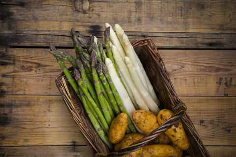 Weißer und grüner Spargel und neue Kartoffeln im Weidenkorb, lizenzfreies Stockfoto