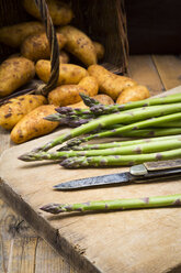 Green asparagus and pocket knife on wooden board - LVF004796