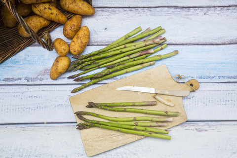 Grüner Spargel und Taschenmesser auf Holzbrett, lizenzfreies Stockfoto