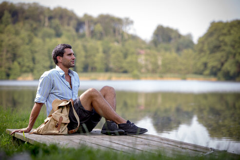 Porträt eines jungen Mannes, der auf einem Steg am See sitzt - ZOCF000060