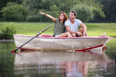 Young couple sitting in a rowing boat on lake looking at distance - ZOCF000063