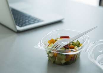 Plastikschüssel mit Salat auf dem Schreibtisch im Büro - UUF007090