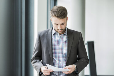 Businessman reading document - UUF007118