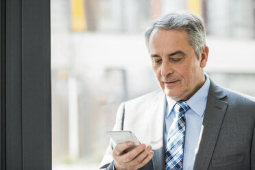 Senior businessman looking on cell phone - UUF007128