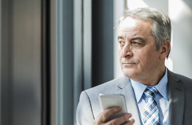 Senior businessman holding cell phone - UUF007129