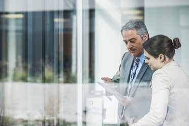 Senior businessman and young businesswoman sharing digital tablet - UUF007132