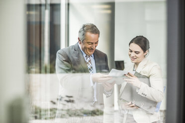 Senior businessman and young businesswoman looking at papers - UUF007134