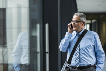 Senior businessman on cell phone at the window - UUF007158