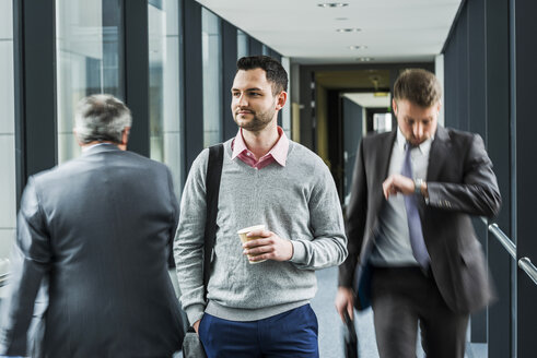 Calm businessman in contrast to businessmen in a hustle - UUF007163