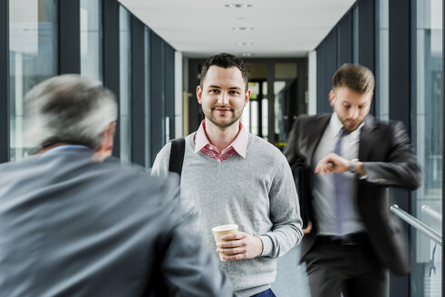 Calm businessman in contrast to businessmen in a hustle - UUF007164