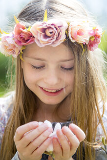 Porträt eines lächelnden Mädchens mit Blumenkranz, das eine Magnolienblüte in den Händen hält - SARF002700