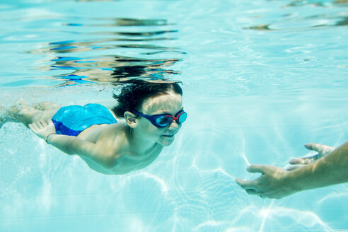 Young boy diving to mother, under water, swimming pool - ZOCF000066