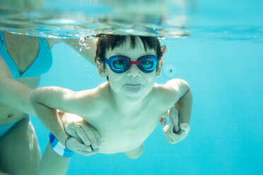 Young boy diving, mother is helping, sticking out tongue, under water, swimming pool - ZOCF000068