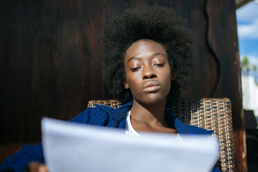 Portrait of young woman sitting in a street cafe looking at papers - KIJF000334