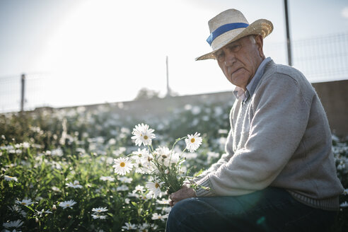 Porträt eines älteren Mannes mit gepflückten Blumen in seinem Garten - JRFF000580