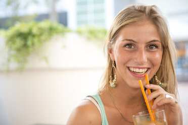 Portrait of happy young woman with drink at outdoor cafe - ZOCF000078