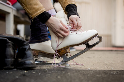 Close-up of woman putting on ice skates - ZOCF000079