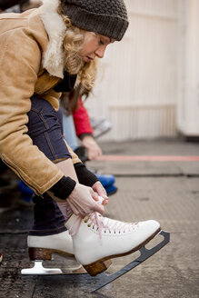 Young woman putting on ice skates - ZOCF000080