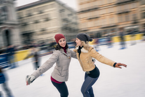 Zwei glückliche Freunde beim Schlittschuhlaufen auf einer Eisbahn im Freien - ZOCF000083