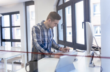 Young man using computer in office - MGOF001779